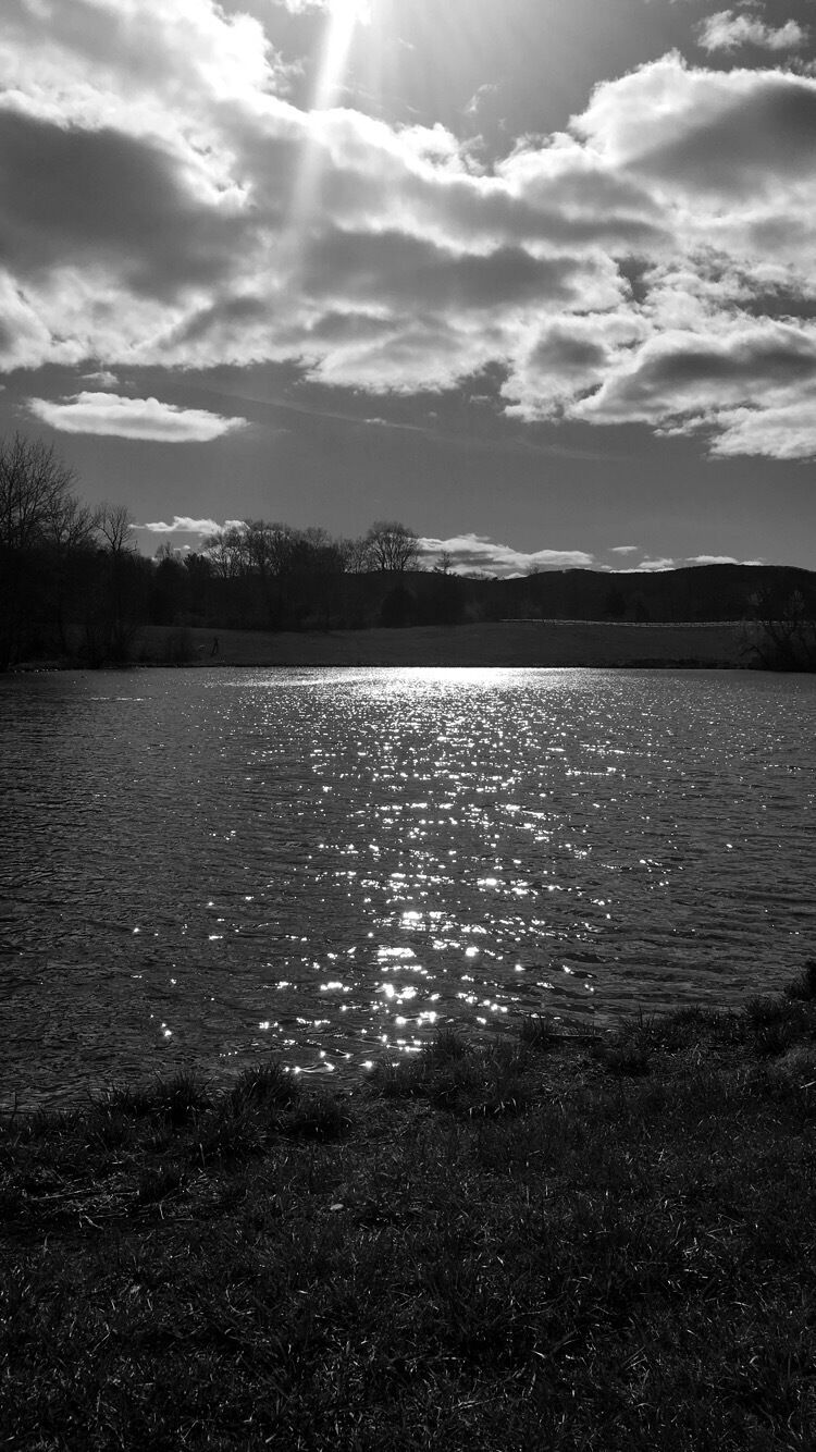A body of water reflecting sunlight with clouds in the sky.