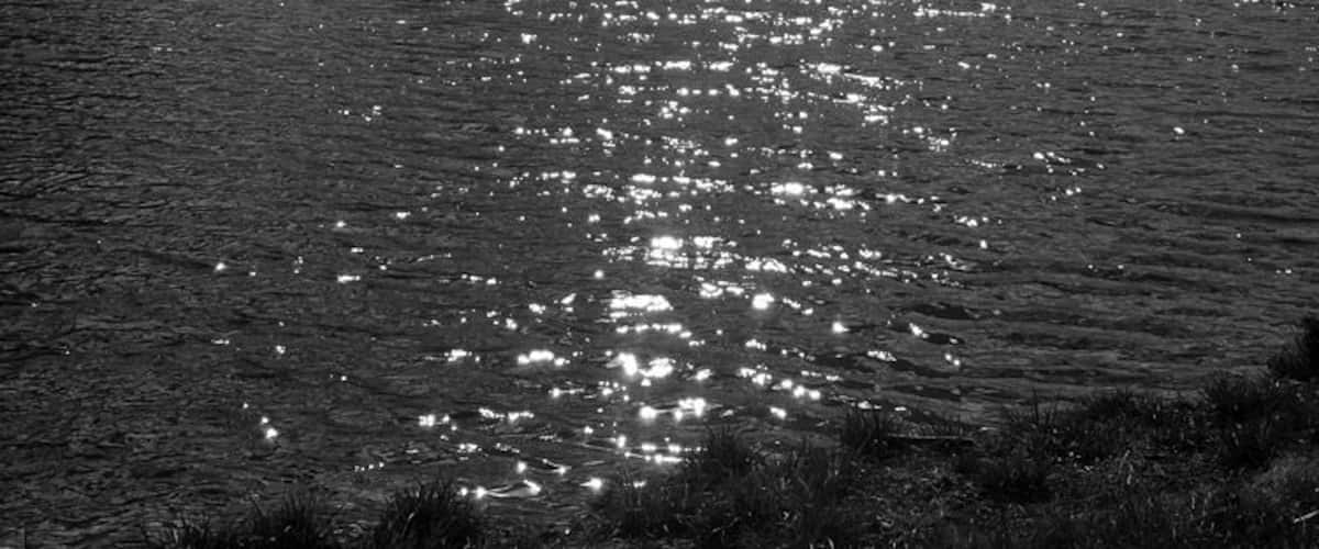 A body of water reflecting sunlight with clouds in the sky.