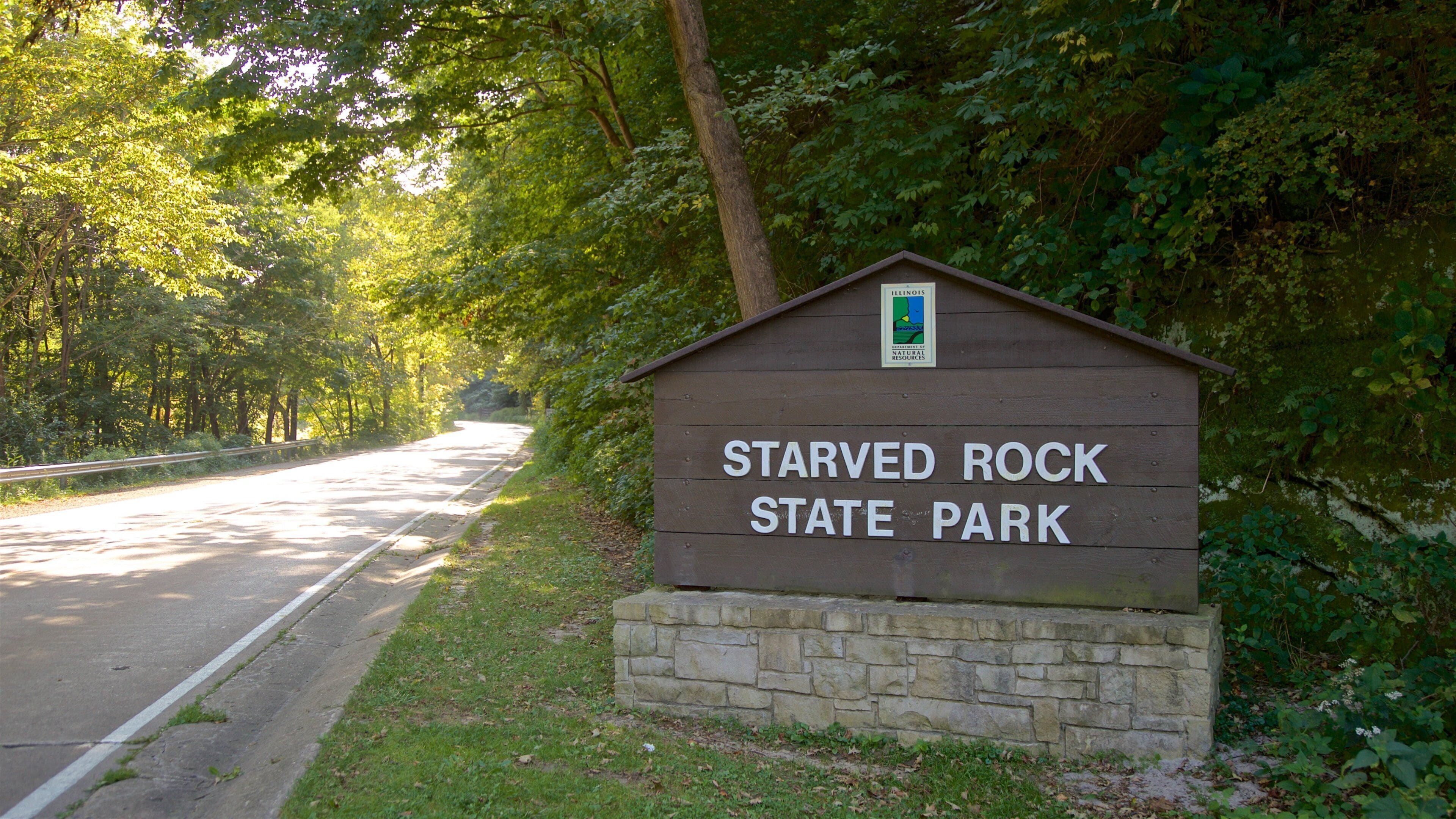 A sign for Starved Rock State Park with a road leading into the park.