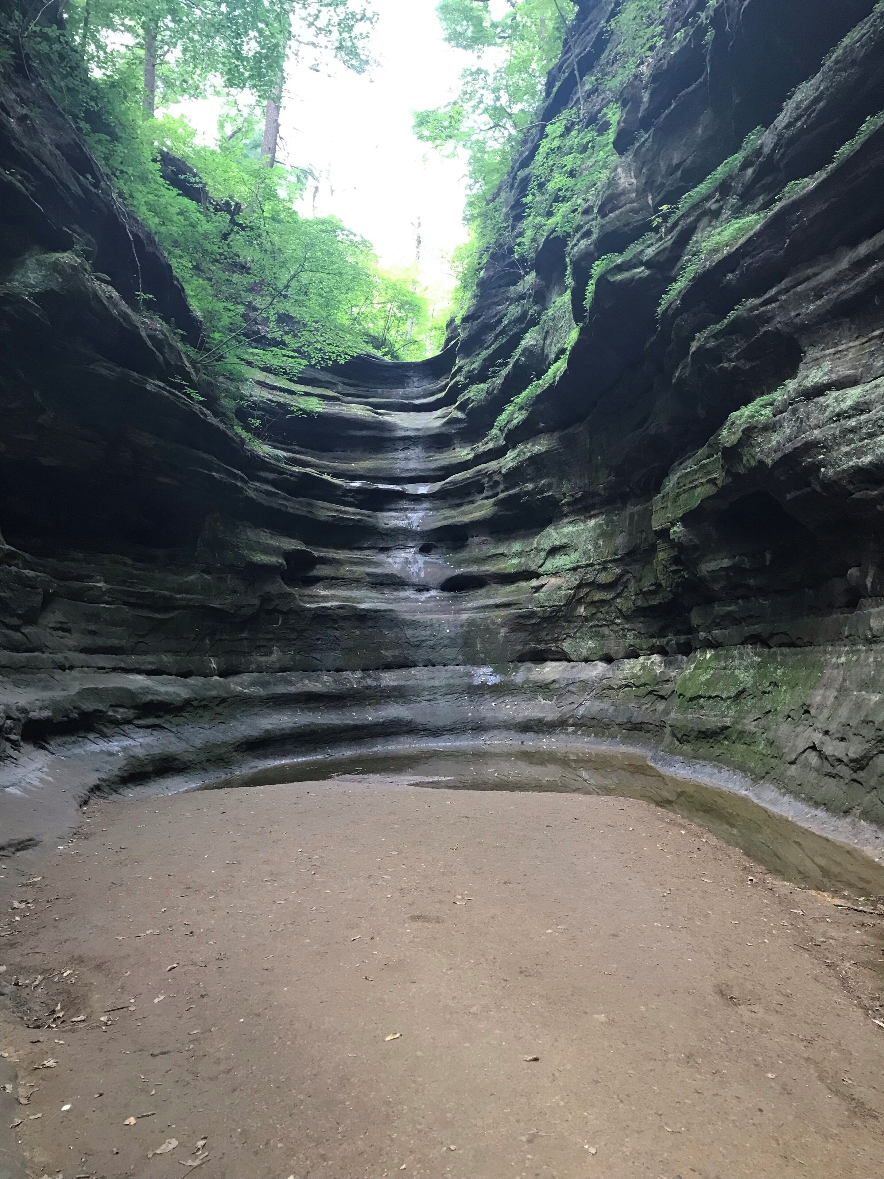 Un canyon étroit, traversé par un ruisseau, avec une zone sablonneuse au fond.