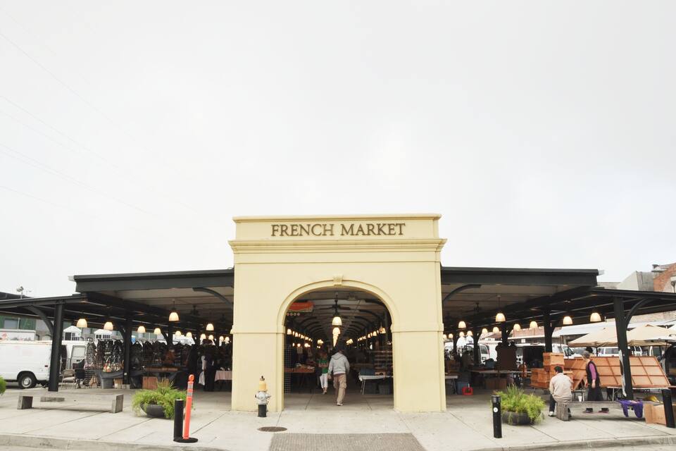 Una entrada al Mercat Francès amb una passarel·la coberta i llums penjants.