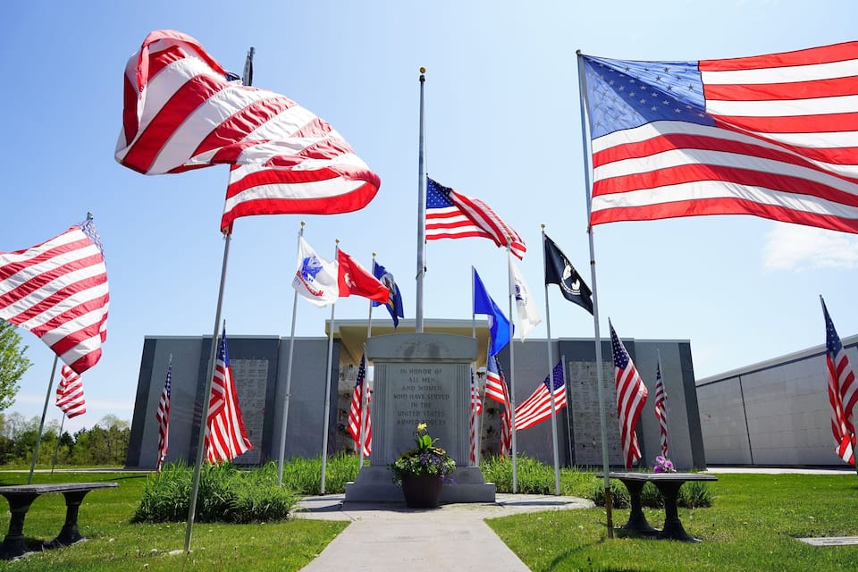 A memorial with multiple American flags and a commemorative plaque.