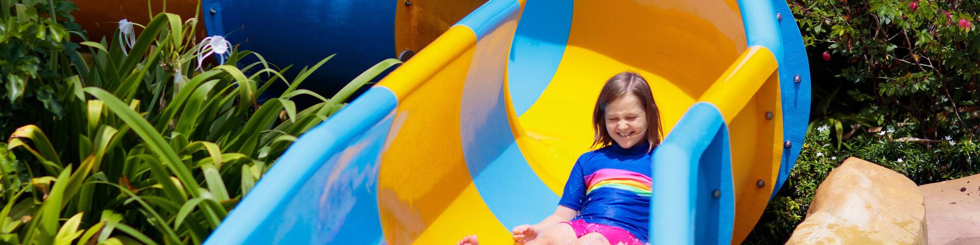 Kids on water slide in aqua park. Summer vacation