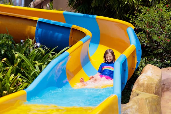 Kids on water slide in aqua park. Summer vacation