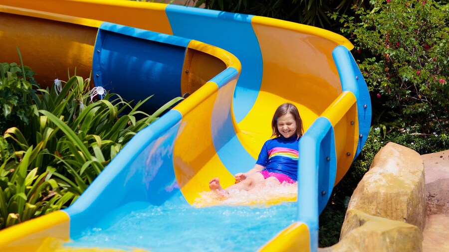 Kids on water slide in aqua park. Summer vacation