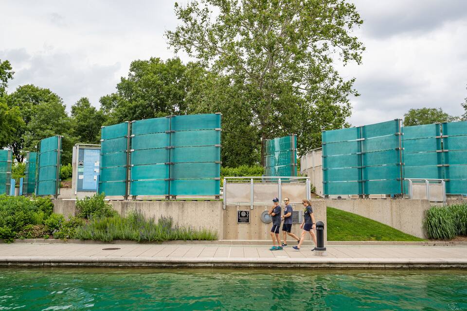 Un chantier de construction aux teintes verdâtres, avec un mur en béton et une clôture métallique.