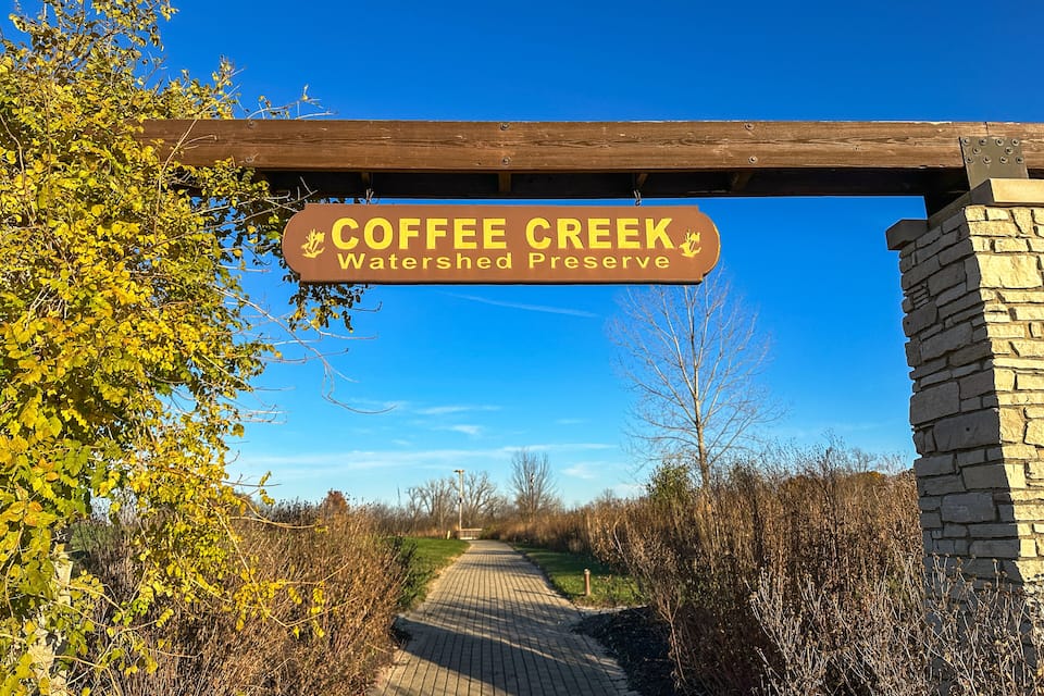A pathway leading to a sign reading "Coffee Creek Watershed Preserve."