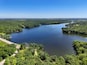 A large lake surrounded by dense forests and a road.