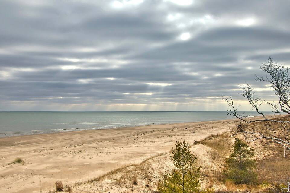 A beach with dunes and a cloudy sky.