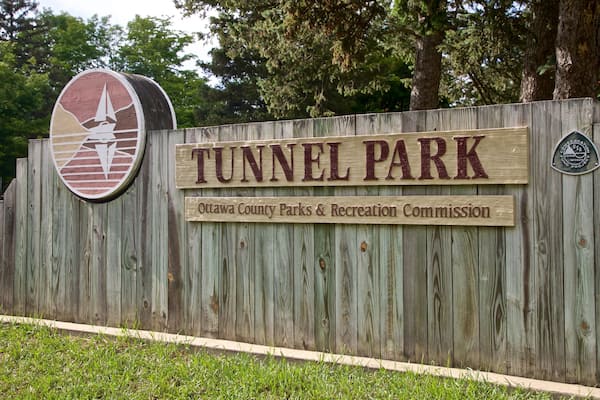 Uma placa de madeira para o Parque Tunnel, com um logotipo e o nome da Comissão de Parques e Recreação do Condado de Ottawa.