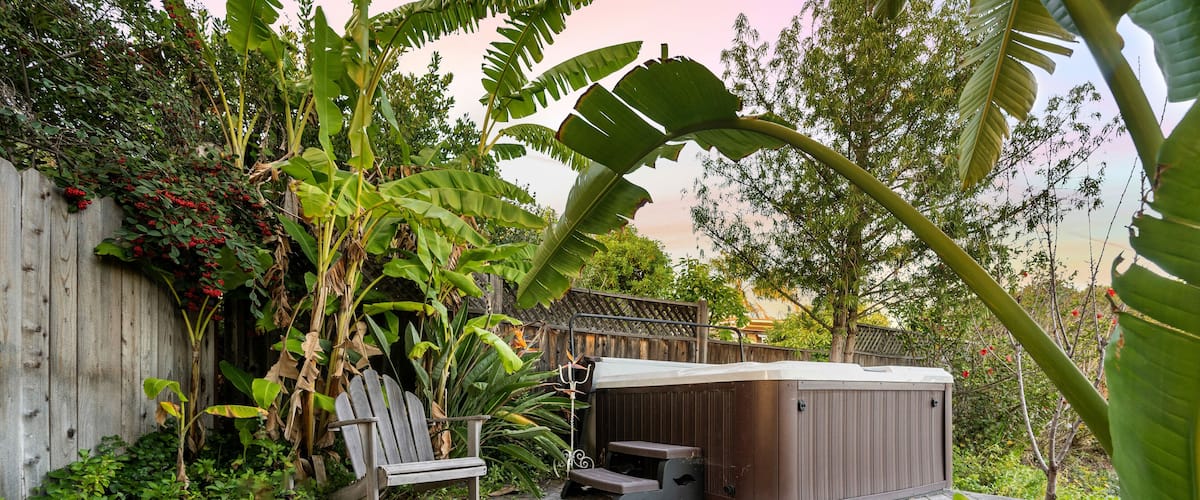 Wooden deck featuring an outdoor hot tub surrounded by lush greenery