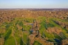 Vista aerea di un campo da golf con diverse aree verdi, ostacoli d'acqua e una grande distesa d'acqua.
