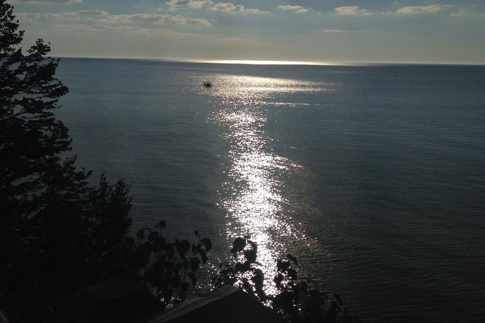 A sunset over a calm sea with sunlight reflecting on the water.