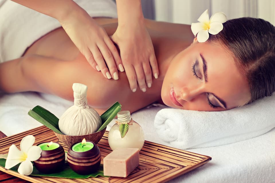 A person receiving a massage with a tray of spa products.