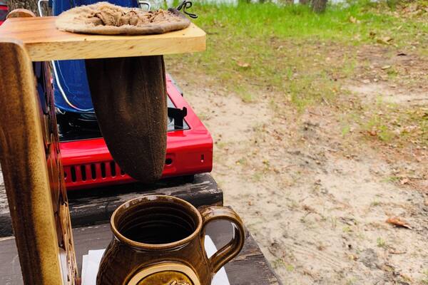 Une table en bois sur laquelle se trouvent une tasse portant l’inscription « Michigan Awesome » et une pizza sur un grill.