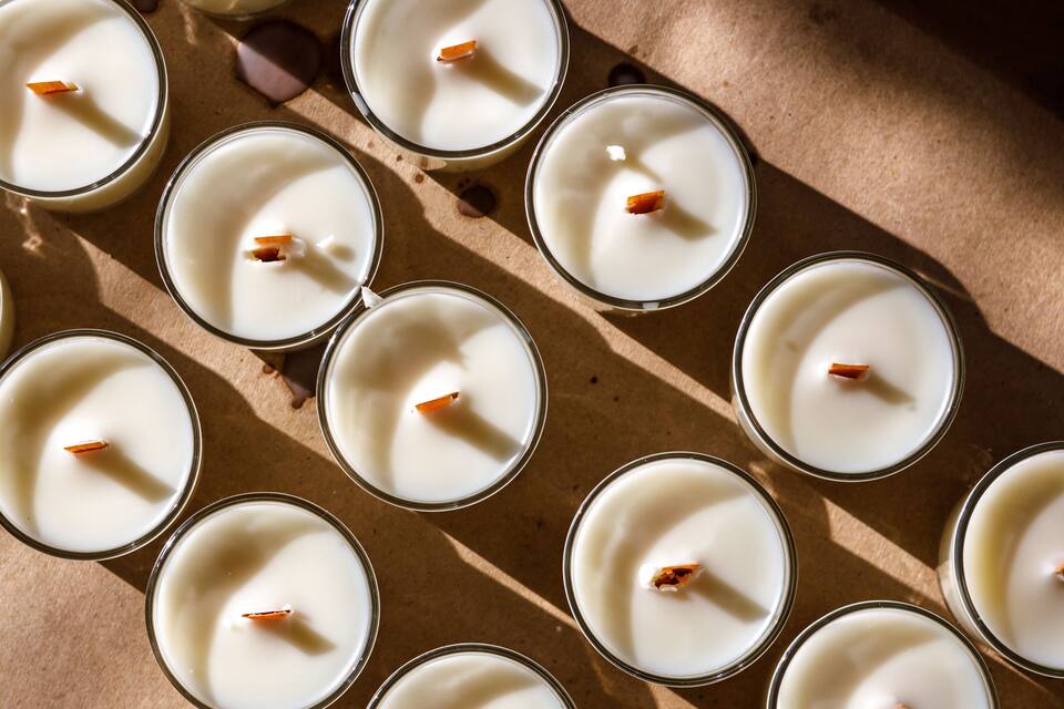 Multiple lit candles with orange wicks on a brown surface.