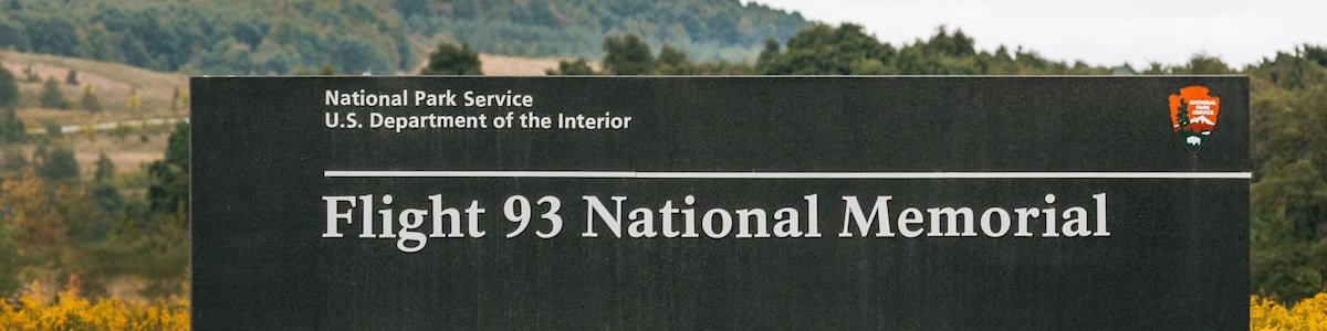 Un panneau indiquant le site du Mémorial national du vol 93, avec en arrière-plan un champ et des collines.