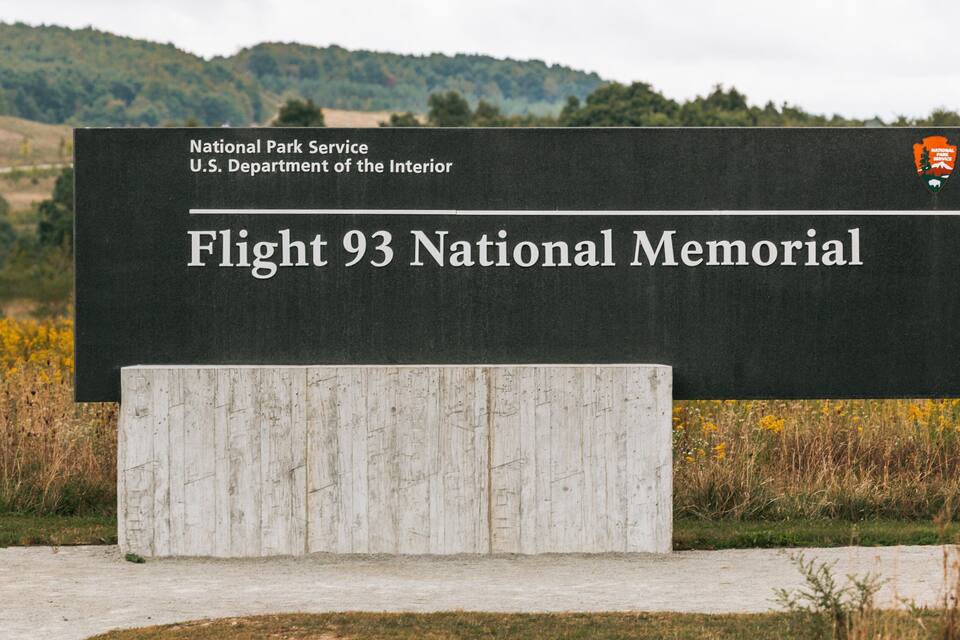 A sign for Flight 93 National Memorial with a backdrop of a field and hills.