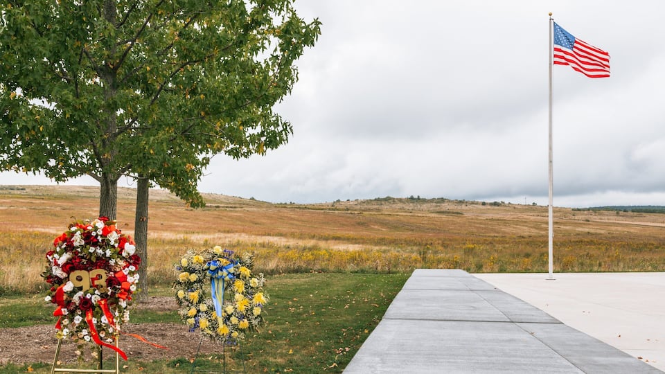 A memorial with two floral tributes and an American flag in a grassy field.