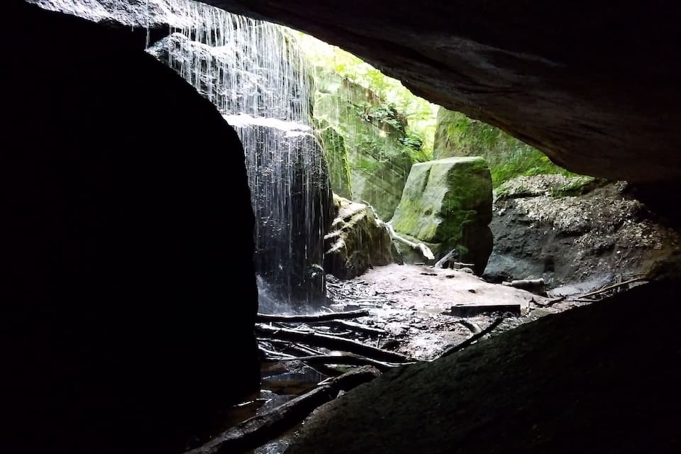 A waterfall cascading through a rocky cave entrance.