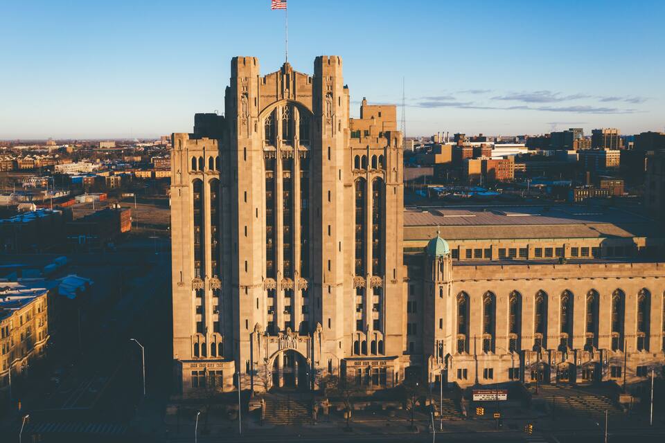 A large, historic building with two towers and a flag.