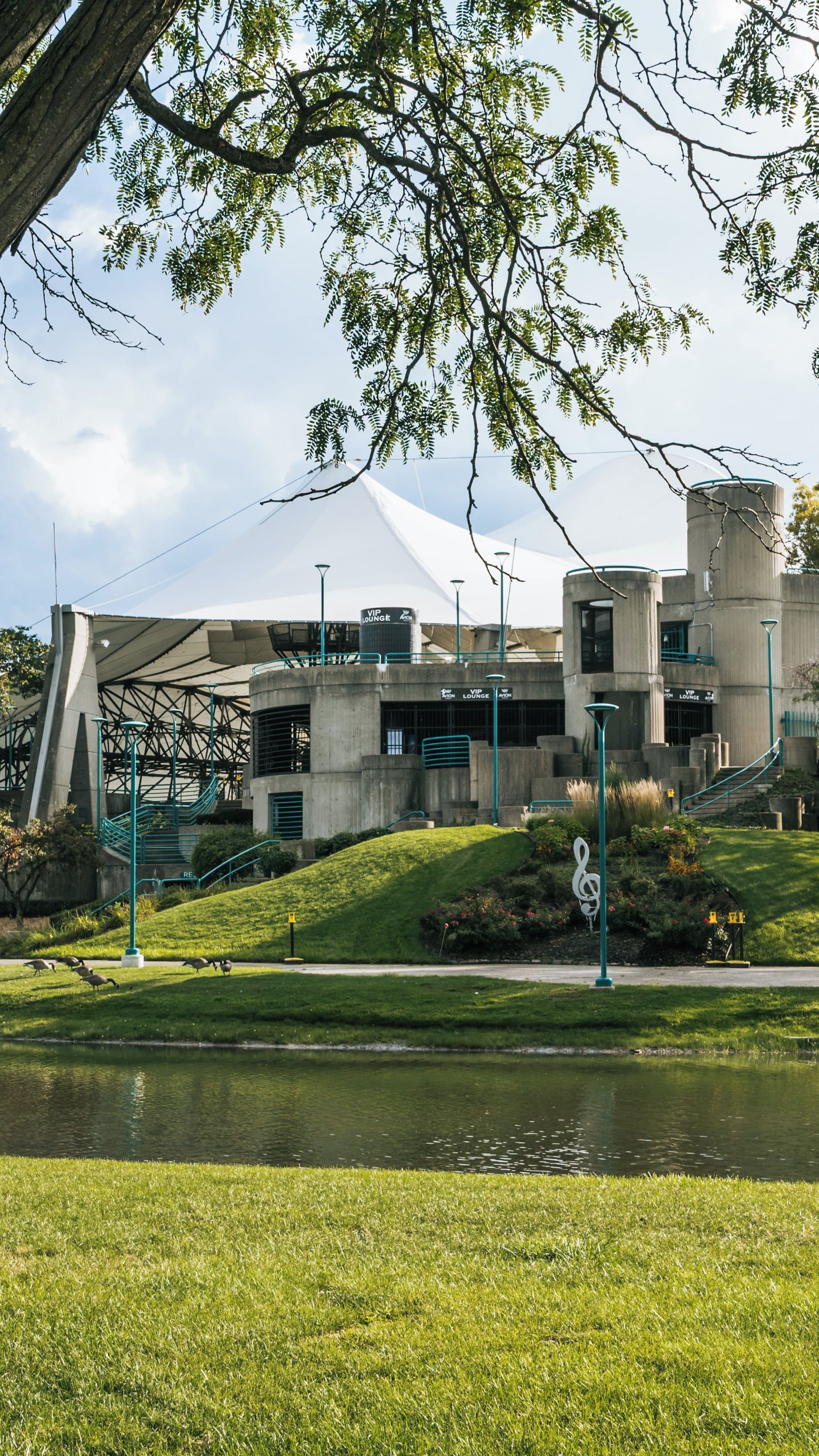A modern building with a unique architectural design, surrounded by a grassy area and a body of water.