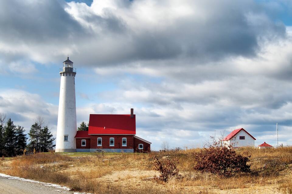 A lighthouse, a red-roofed building, and a white building with a red roof.
