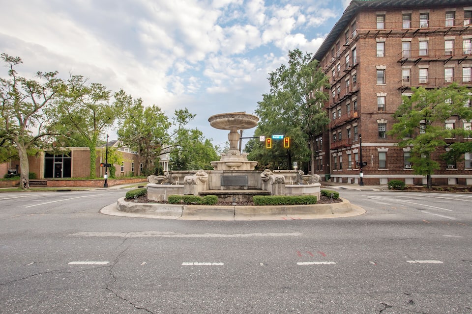 A roundabout with a central fountain, surrounded by trees and buildings.