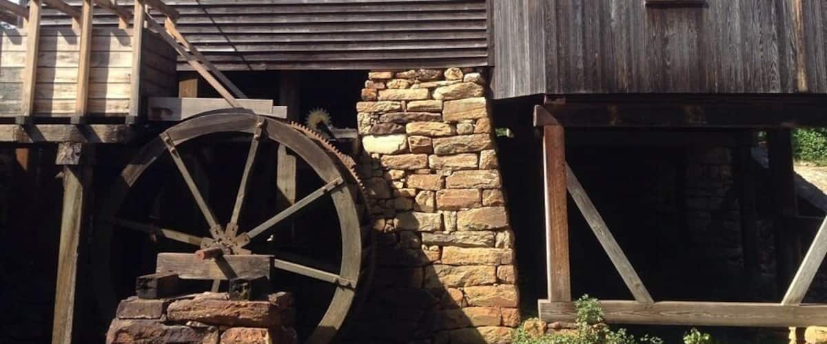 A wooden mill with a water wheel and stone foundation.