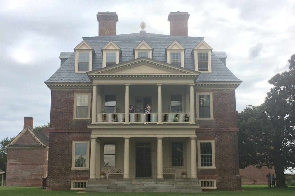 A large brick house with a central porch and multiple windows.