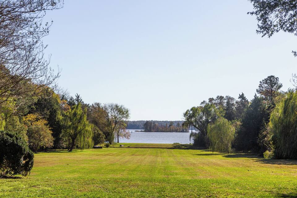 A grassy park with a lake and trees.