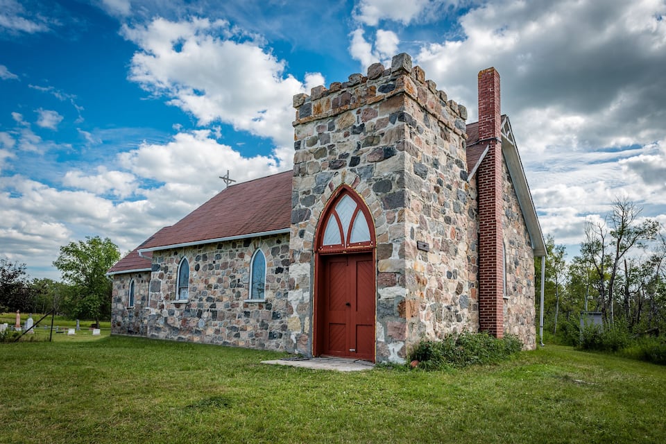 A stone church with a red door and arched windows.