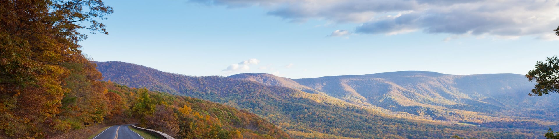 A winding road through a mountainous landscape with autumn foliage.