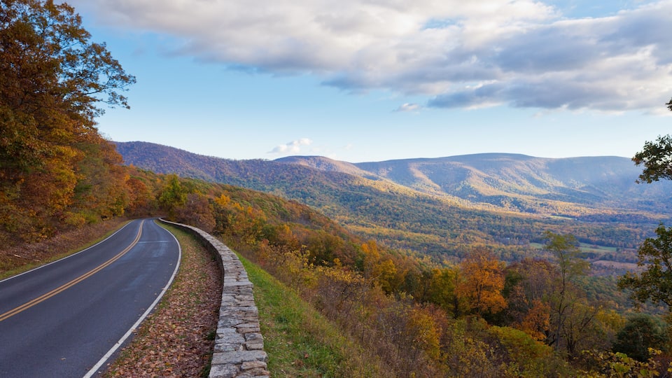A winding road through a mountainous landscape with autumn foliage.