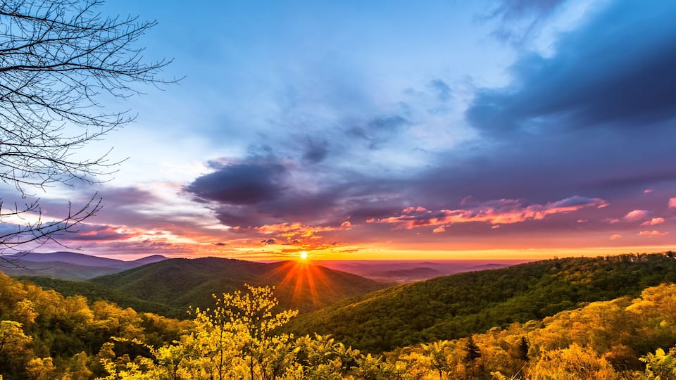 A sunset over a mountainous landscape with dense forest.