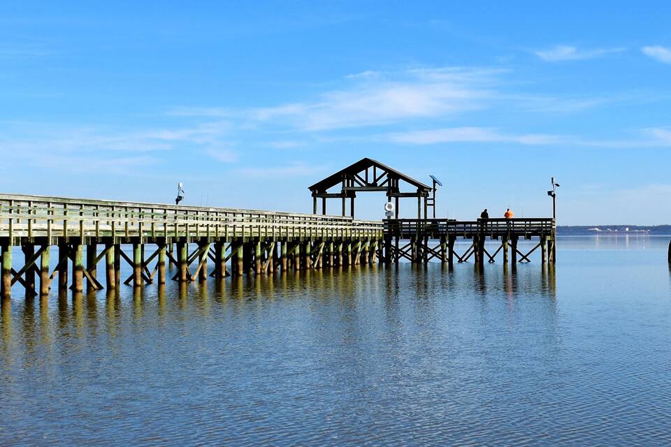 Un muelle de madera que se adentra en aguas tranquilas, con una estructura cubierta al final.
