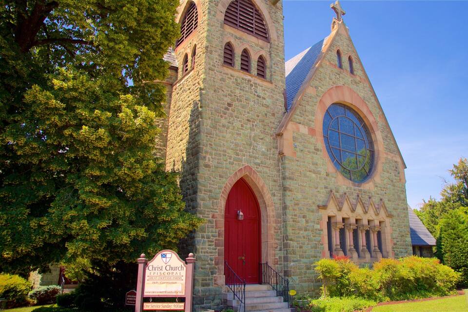 A stone church with a red door and a large circular window.