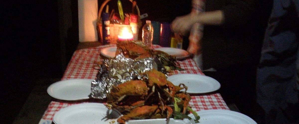 A table set for a meal with seafood, including crabs and shrimp, and a lit candle.