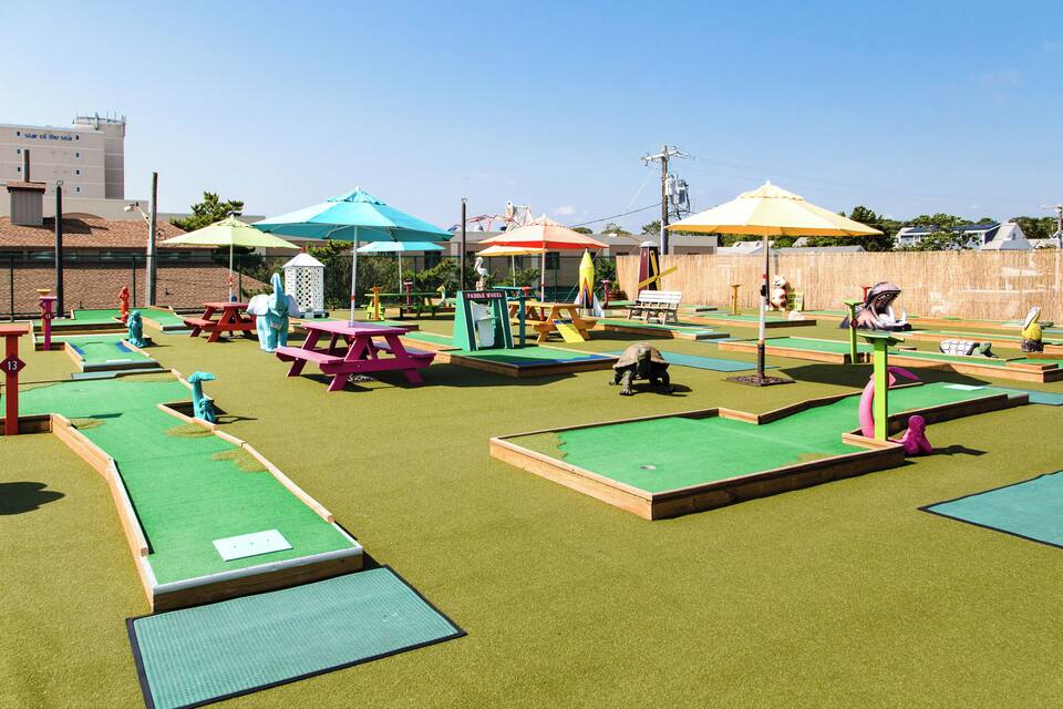 A miniature golf course with colorful umbrellas and various obstacles.