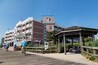 Een vogelvlucht van een houten looppad met fietsers, een kiosk en een gebouw met balkons en vlaggen.