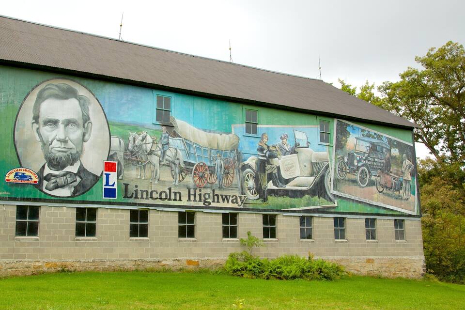 A mural on a building depicting historical scenes and the Lincoln Highway.
