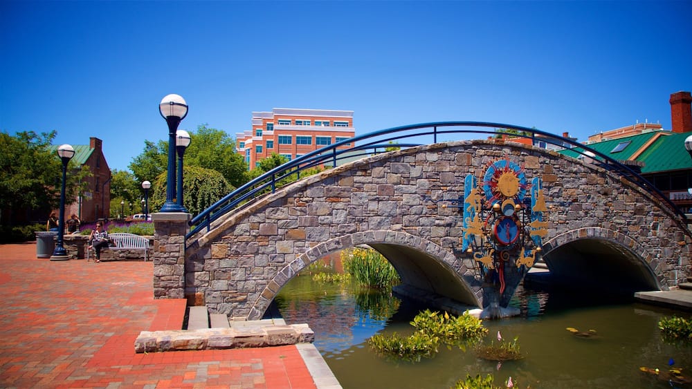 A stone bridge with a decorative mural, a pond, and a red brick pathway.