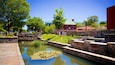 A canal with water lilies, a stone bridge, and a red building with a green roof.