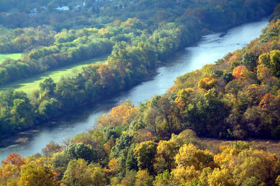 A river winding through a densely wooded area with autumn foliage.