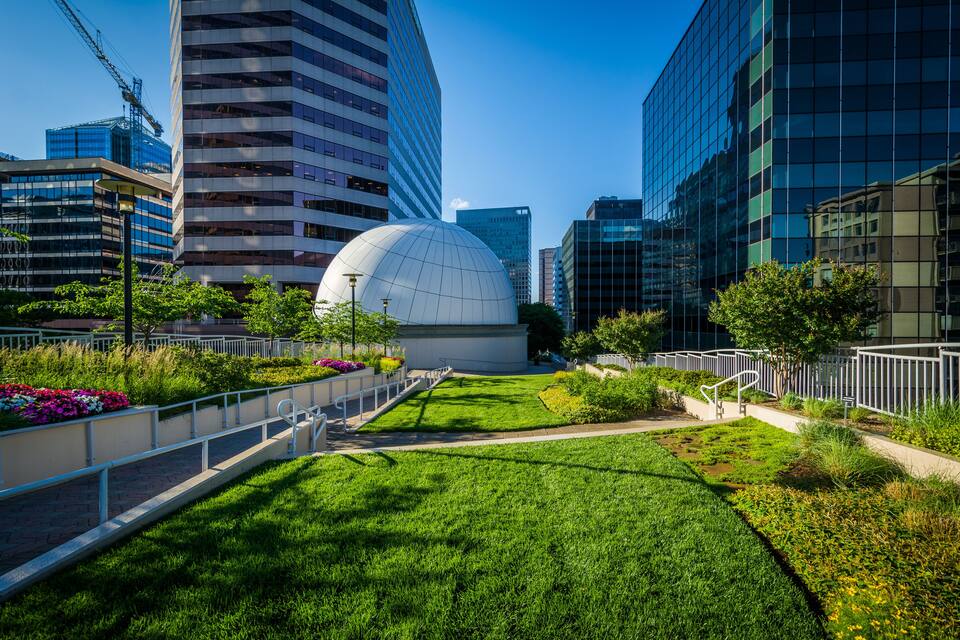 Paisagem urbana moderna com um edifício esférico, áreas verdes e altos edifícios comerciais.