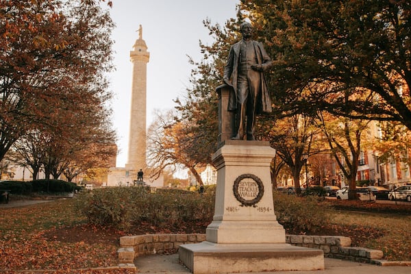 George Peabody Library featuring a statue or sculpture, a park and autumn leaves