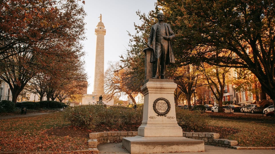 George Peabody Library featuring a statue or sculpture, a park and autumn leaves