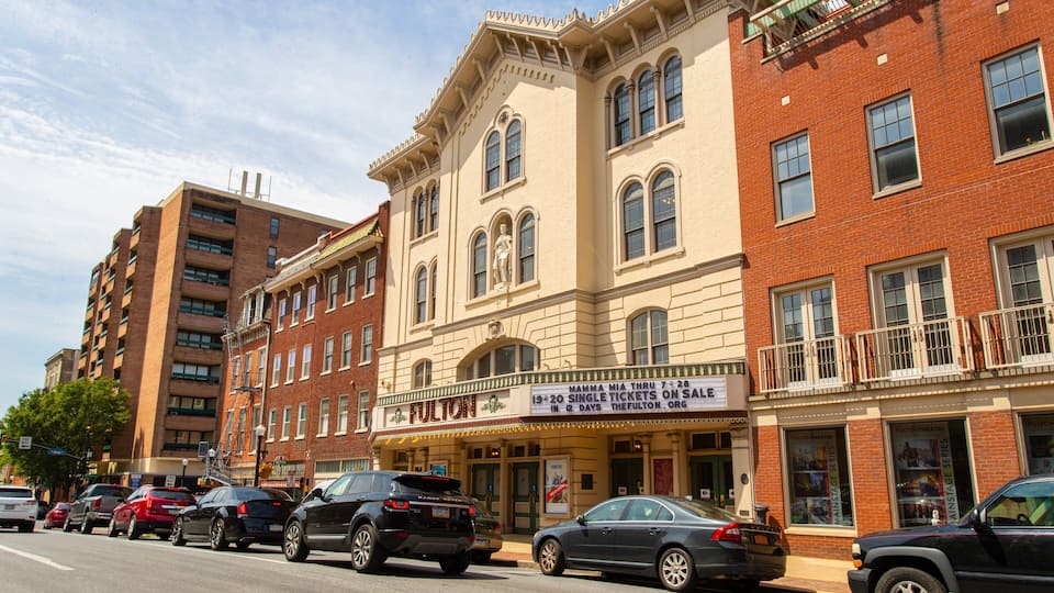 A street with multi-story buildings, including a theater with a marquee advertising a matinee show.
