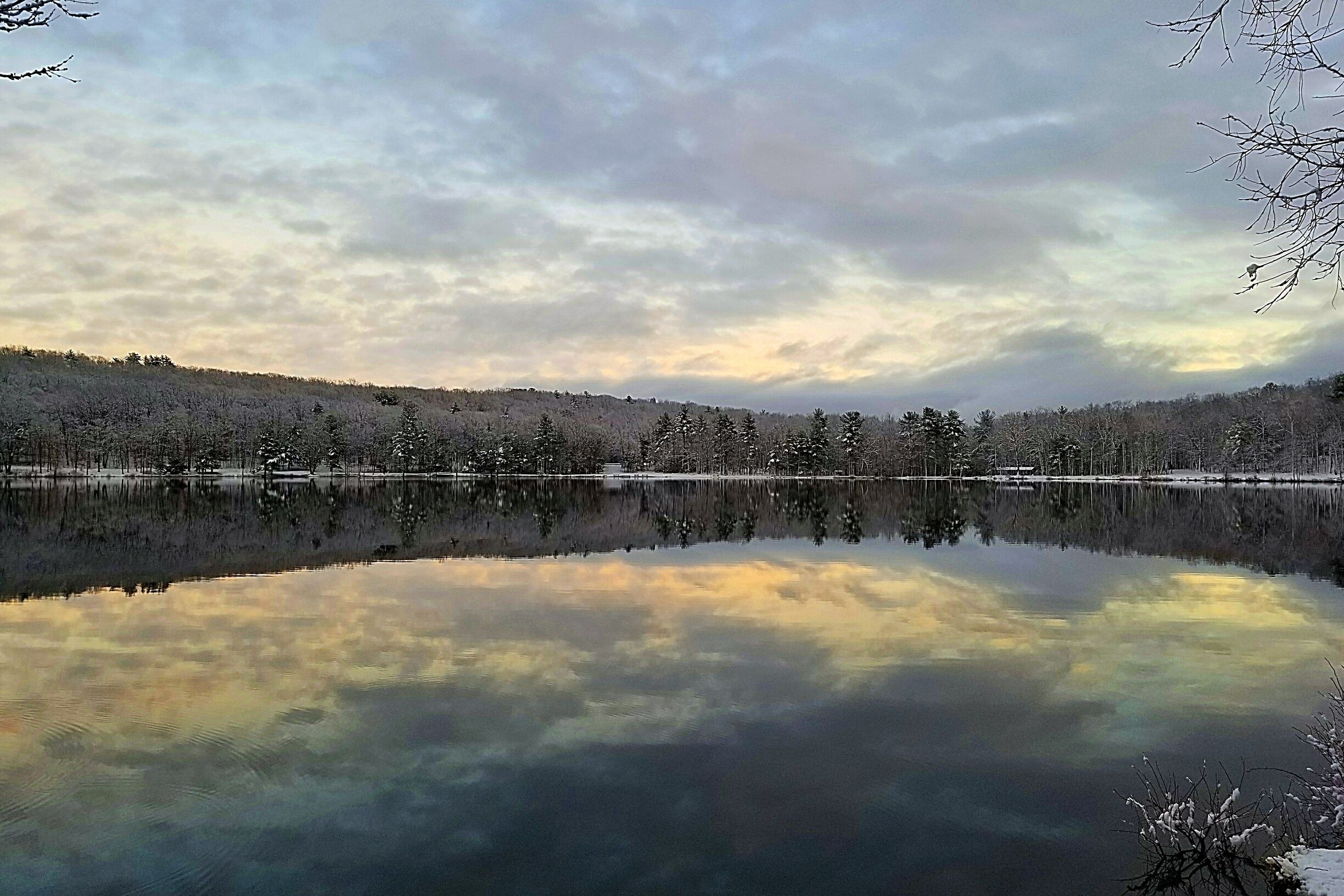 A calm lake reflecting the sky and trees.