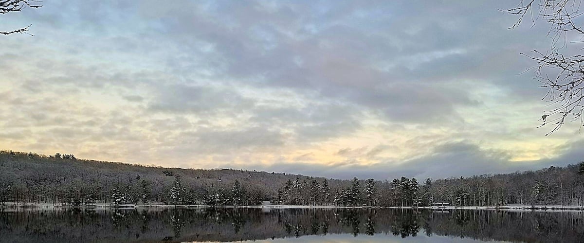 A calm lake reflecting the sky and trees.